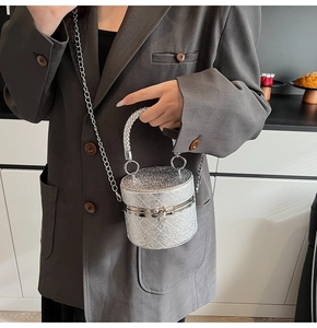 Detailed macro view of silver sequin bucket bag with quilted pattern and chain strap