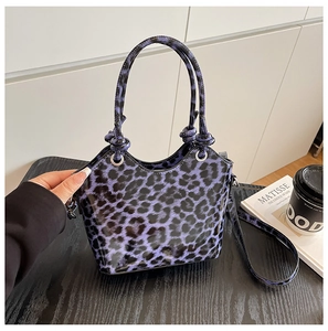 Detail of purple leopard print handbag with glossy texture and knotted handle design
