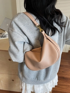 Pink crescent hobo bag with pebble leather texture and golden X-shaped hardware