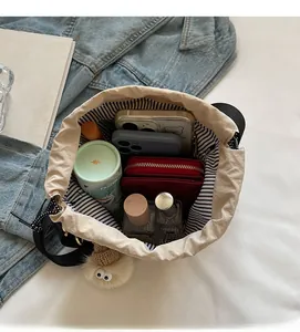 Vue de dessus de l'intérieur du sac seau beige à cordon avec doublure rayée et objets