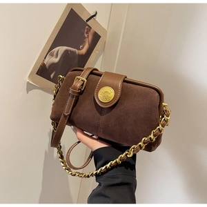 Detailed view of brown frosted leather doctor bag with gold coin emblem and chain handle