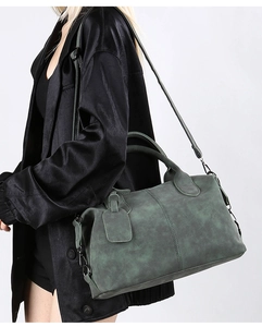 Detail view of large dark green Boston bag with top handles and adjustable strap