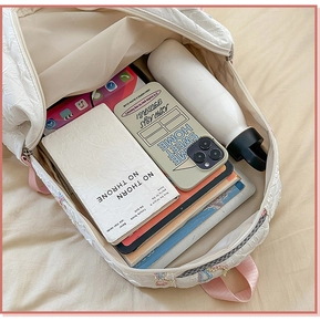Spacious interior of white quilted backpack holding a tablet, notebook, and water bottle