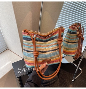 Détail du sac seau tissé arc-en-ciel avec des lanières en cuir marron et le logo de la marque