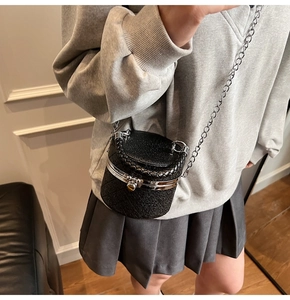 Detail of a black quilted leather mini bucket bag with silver chain strap and metal lock