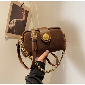 Detail of dark brown suede doctor bag with vintage gold emblem and chain strap
