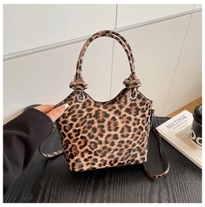 Macro shot of glossy leopard print handbag showing knotted handle and metal eyelet details