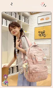Detail of pink quilted backpack for students featuring multiple zipper pockets and cute charms
