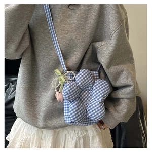 Detail of blue plaid bucket bag with pearl chain, green bow and tulip charm accents