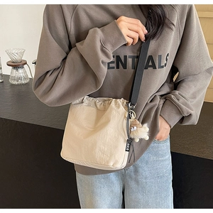 Détail du sac seau beige à cordon avec bandoulière noire et charm en peluche doux