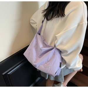 Detail of lavender nylon messenger bag featuring BNT embroidery and adjustable strap