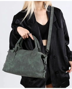 Detail of dark green vintage boston bag featuring matte texture and double stitching