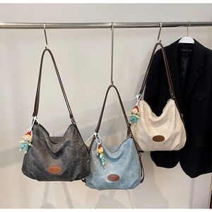 Trois sacs cabas multicolores avec étiquettes logo en cuir et gris-gris sur rack métal