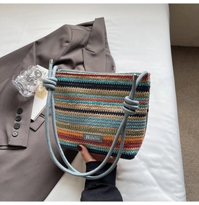 Détail du sac seau tissé à rayures colorées avec des anses en cuir bleu nouées