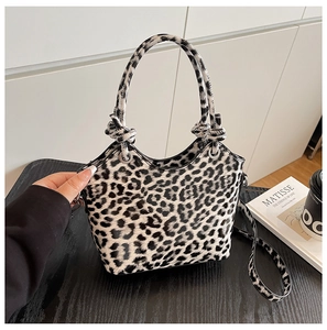 Detailed view of leopard print handbag with knotted handles and a removable shoulder strap