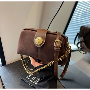 Close-up of vintage brown suede doctor bag featuring a gold emblem and chain strap