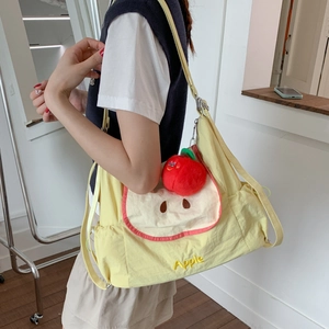 Détail du sac en toile jaune avec broderie pomme et breloque en peluche 3D
