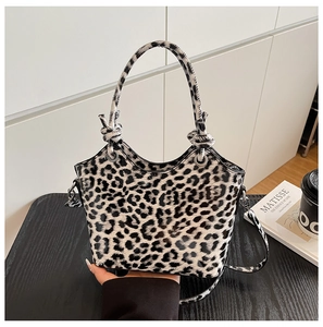 Close-up of leopard print tote bag with knotted handle and glossy leather texture on a table