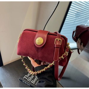 Detail of burgundy suede and leather doctor bag with gold chain and circular emblem