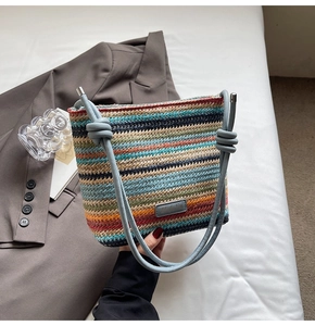 Gros plan du sac seau tissé à rayures arc-en-ciel avec bretelles bleues et logo cuir