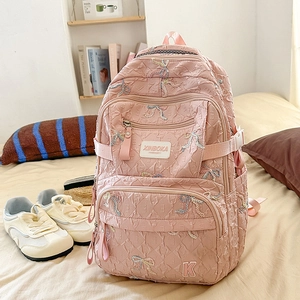 Detail of pink quilted backpack featuring colorful bow embroidery and multi-pocket design