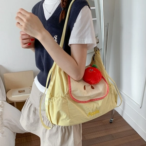 Détail d'un sac cabas en nylon jaune vif avec broderie Apple et breloque pomme en peluche