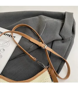 Detail showing an adjustable tan leather strap with silver buckle on a woven beach bag