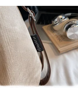 Détail d'un cabas en tissu texturé beige avec lanières en cuir marron et étiquette de marque