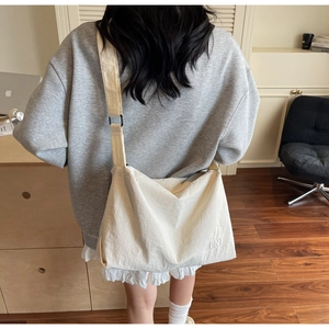 Détail d'un grand sac bandoulière beige en toile avec broderie BNT et bandoulière