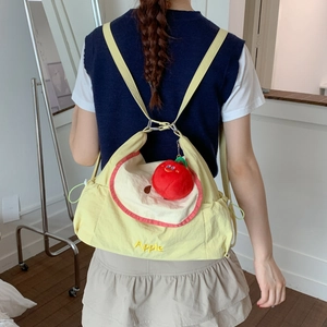 Gros plan du sac en toile jaune clair avec broderie Apple et pendentif en peluche rouge