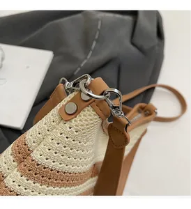 Detail view of woven bucket bag featuring brown leather trim and silver metal hardware