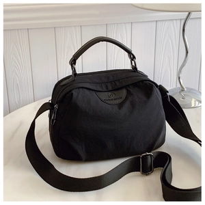 Dettaglio borsa in nylon nero con manico in pelle su superficie di marmo