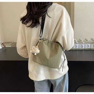 Mini sac seau en nylon vert olive avec cordon de serrage et breloque en peluche sur modèle