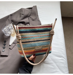 Détail du sac seau tissé arc-en-ciel avec bandoulière en cuir et nœud décoratif