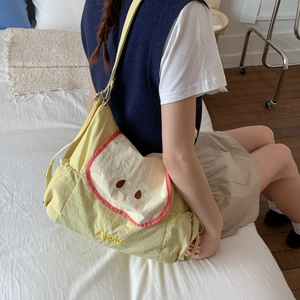 Détail du sac bandoulière en toile jaune avec rabat motif pomme et bandoulière réglable