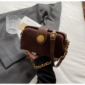 Detail of vintage brown doctor bag featuring frosted leather texture and gold metal clasp