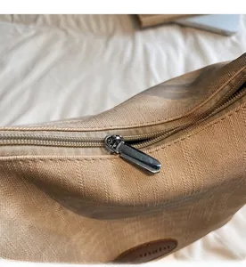 Détails de la fermeture éclair argentée et logo en cuir sur le sac fourre-tout kaki