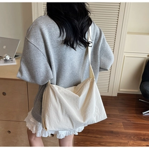 Close-up of a large beige canvas tote bag with BNT logo worn by a model in a cozy room