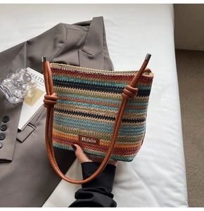 Détail du sac seau tissé à rayures colorées avec poignée nouée en cuir brun et logo