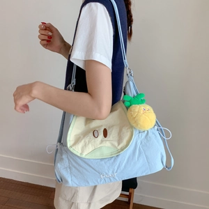 Détail du sac cabas bleu clair en toile avec motif poire et breloque ananas jaune