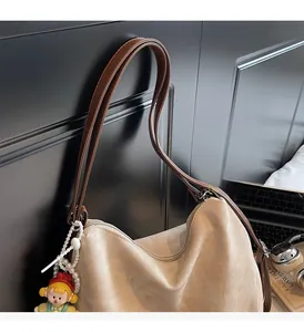 Gros plan du sac hobo avec des lanières en cuir marron et un charm de poupée