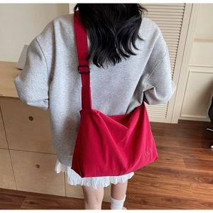 Détail du sac bandoulière en toile rouge avec broderie BNT et bandoulière réglable