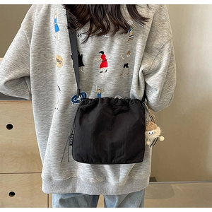 Détail d'un sac bandoulière noir en nylon avec étiquette KAKA et charm en peluche