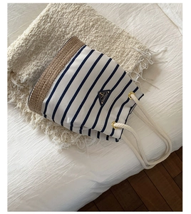 Dettaglio della borsa a secchiello in tela a righe bianche e blu con base in paglia
