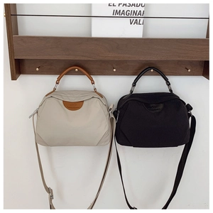 Dettaglio di borse tote in nylon minimaliste in beige e nero appese a un gancio di legno