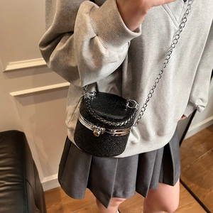 Mini black quilted leather cylinder bucket bag with chain strap and top handle shown on model