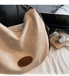 Détail de la texture du sac cabas beige avec étiquette en cuir marron et sangle réglable