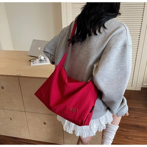 Détail d'un grand sac bandoulière en toile rouge avec broderie BNT et large bandoulière