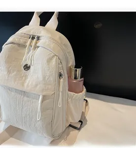 Detail of cream nylon backpack showing elastic side pocket with a pink bottle