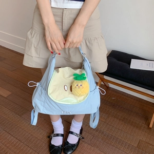 Détail du sac fourre-tout bleu et beige avec un joli pendentif en peluche ananas